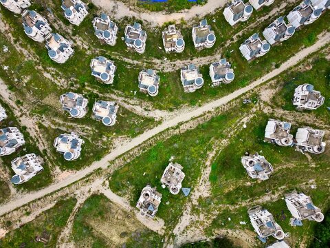 Drone view of abandoned fairy tale castles in a ghost town in Turkey with overgrown land and winding paths