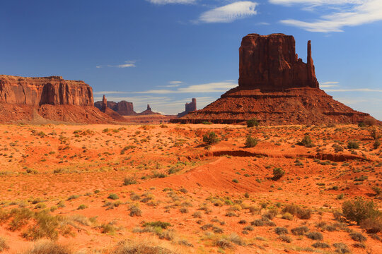 Views of rock formations in Monument Valley with blue sky and desert landscape in Utah