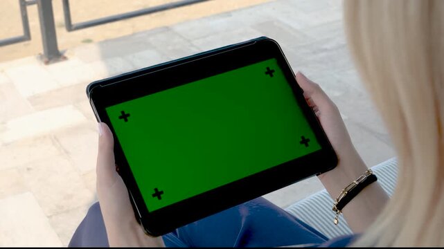 Close up of hands holding a tablet computer with green screen chroma key and markers for motion tracking while sitting outdoors for digital product demonstration session