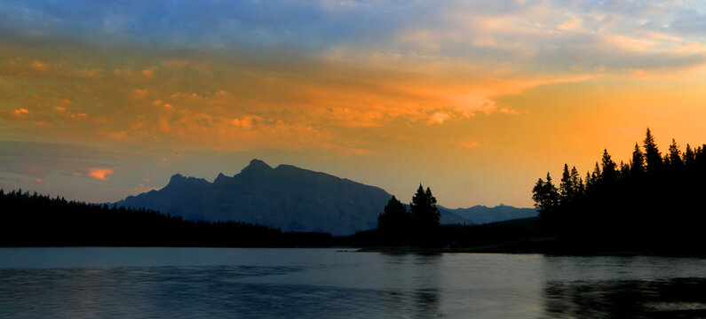 View of Jack Lake with Rocky Mountains under sunset sky near Banff in Canada
