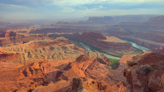 Visitors explore views of rocky terrain and winding river in Canyonlands National Park at sunset in Utah USA