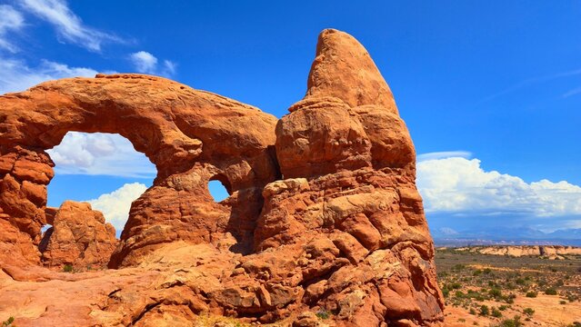 Rock formations stand tall under a bright sky in Arches National Park, Utah, showcasing natural beauty and geological features