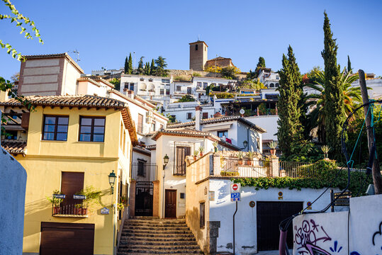 Narrow street leads uphill in the Albaicin neighborhood toward a church tower in Granada Spain