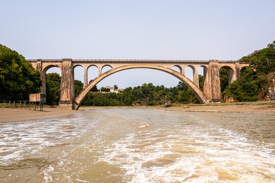 View of Viaduc de Lessard railway viaduct spanning Rance estuary in Brittany, France, with sandy banks and waterway below