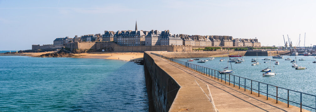 View of Saint-Malo walled city and harbor from stone pier in Brittany France during a sunny day
