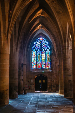 Gothic stone arches and stained glass windows create a serene view inside a church in Dinan, Brittany, France