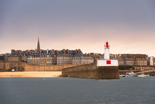 Lighthouse and stone jetty mark entrance of harbor with view of town in Brittany, France