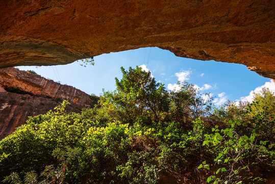 Natural rock arch frames greenery along Barranco de Luna trail in Granada, Spain showcasing sandstone and foliage contrast