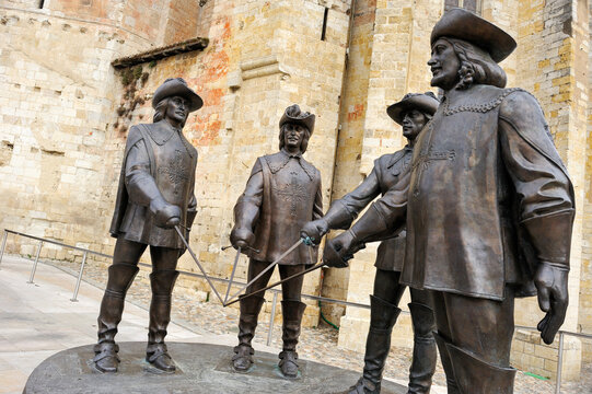 Monumental statue of The Three Musketeers and dArtagnan near a historic cathedral in France