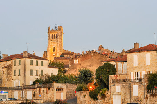 Historic buildings and a clock tower are seen against the evening sky in a town in Gers department, southwest France