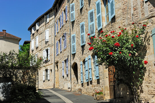 Exploring the narrow street lined with stone buildings and colorful shutters in Figeac, a historic town in France