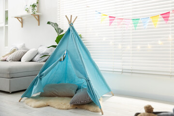 Child's room with toy wigwam, colorful flags and decorative lights. Interior design © New Africa