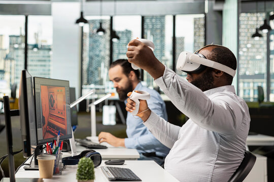 Black game developer designing assets with VR headset at the office, working on spatial video game in space. Engineer uses modeling tools on animation software, creating futuristic virtual world.