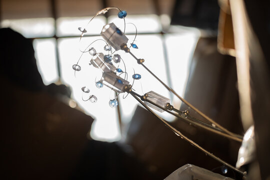 In an old closet, a piece of a beautiful decorative chandelier with rhinestones and pattern springs sticks out from under the trash. High quality photo