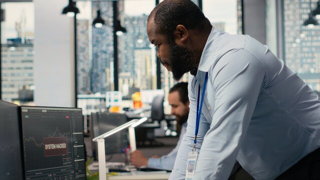 Trader in office alerted by suspicious hacking alert on trading platform dashboard. Brokerage company worker detects hacking attempt on trading software and initiates security protocols