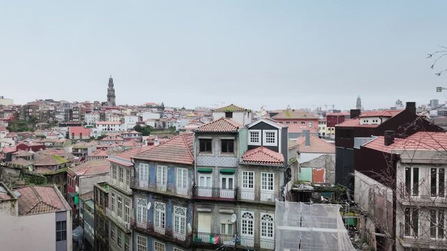 Aerial view of the traditional architecture in Porto, Portugal, featuring historic buildings with colorful tiled facades, old rooftops, and the city skyline under a cloudy sky