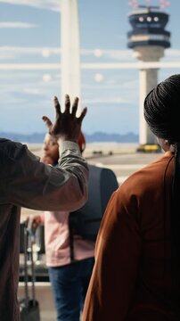 Vertical Video Waving goodbye at airport, sad mother and father, daughter studying abroad, traveling alone and boarding at terminal gate. Supportive parents bid farewell to solo traveler girl student.