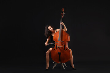 Woman playing double bass on black background © New Africa