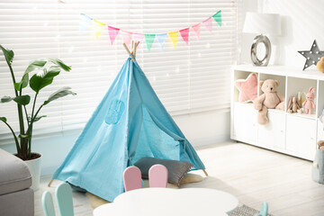 Child's room with furniture, toy wigwam, toys and colorful flags. Interior design © New Africa