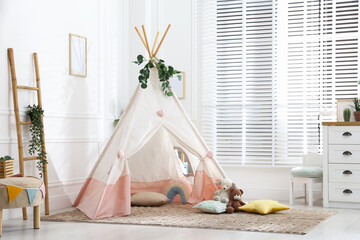 Toy wigwam with pillows, furniture and floral decor in room © New Africa
