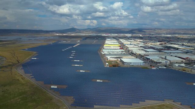 Aerial View of Large Solar Power Plant Next to Industrial Area and Wetland Landscape