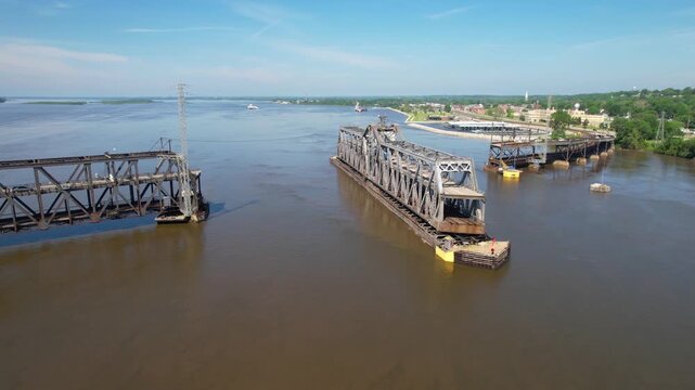 IOWA - 6.24.2024 - Fantastic aerial view circling counter-clockwise around a double-decked swinging truss bridge over the Mississippi River.