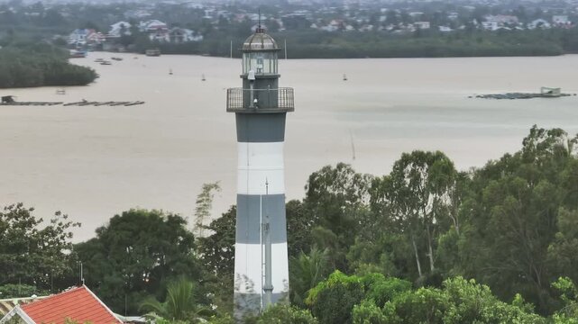 Cua Dai Lighthouse stands tall amidst lush greenery in Hoi An, Vietnam, guiding ships and illuminating the coastal landscape. A beacon of hope and safety for mariners.