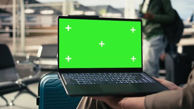 Green screen on laptop near crowd of tourists at the airport gate, ready for boarding plane with luggage and backpacks. Passengers check schedule updates and travel information in terminal.