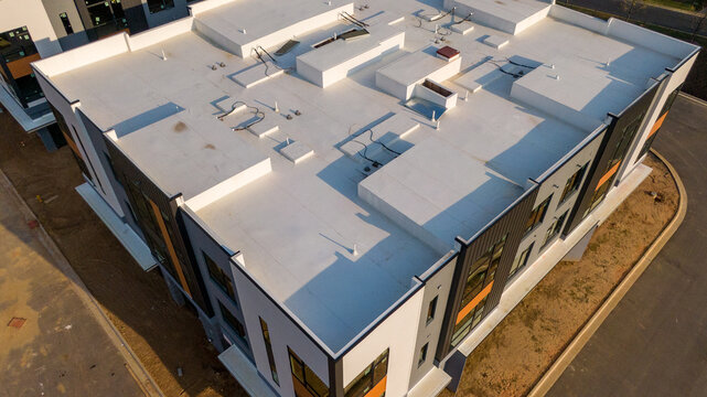 Aerial drone inspection of commercial TPO roof featuring heat-welded seams, HVAC curb flashing, and pipe penetrations.