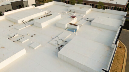 Aerial drone inspection of commercial TPO roof featuring heat-welded seams, HVAC curb flashing, and pipe penetrations. © Oak City Drone