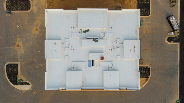 Aerial drone inspection of commercial TPO roof featuring heat-welded seams, HVAC curb flashing, and pipe penetrations.