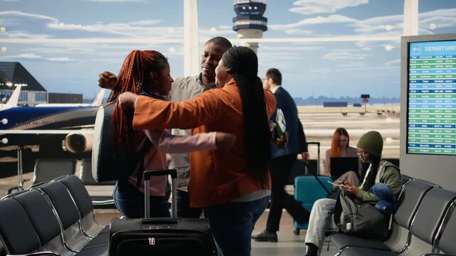 Emotional scene of African American parents hugging daughter in airport terminal, saying a bittersweet goodbye before departure flight. Young traveler leaving to study abroad, solo travel.