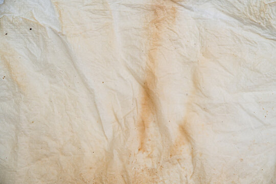 Close up of wrinkled white paper tissue with brown liquid stains and texture