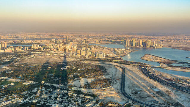 Aerial sunset view of Dubai skyline with a massive tower shadow