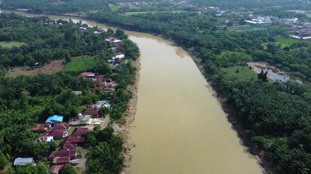 Aerial view of overflowing Wampu River with brown muddy water and red bridge in Stabat, North Sumatra, Indonesia
