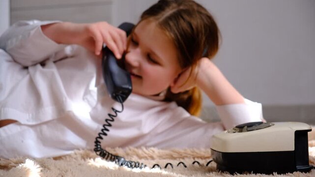 Teenager girl with a vintage rotary phone, talking, whispering. Soft blurred, focus on phone. Pretty teenager girl talking to someone on the phone.	