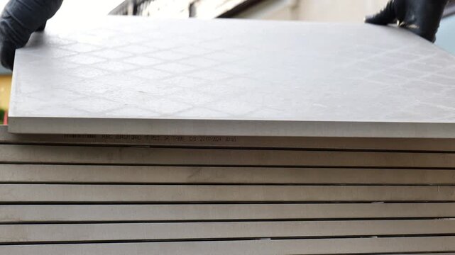 Construction of the terrace .Mens hands lay grey square tiles on the terrace.Laying tiles on fine gravel. 