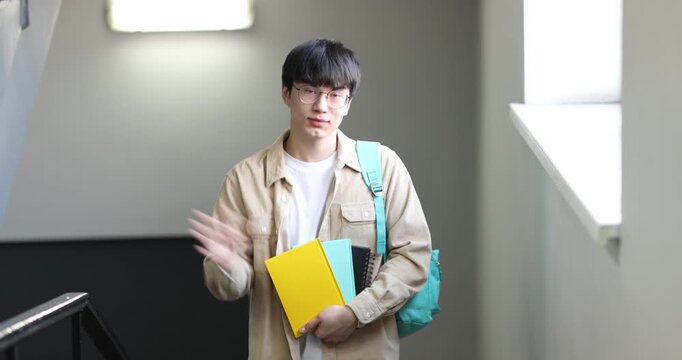 Student with notebooks and backpack walking up stairs indoors