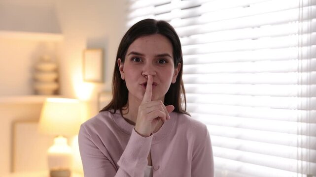 Beautiful woman showing hush gesture at home