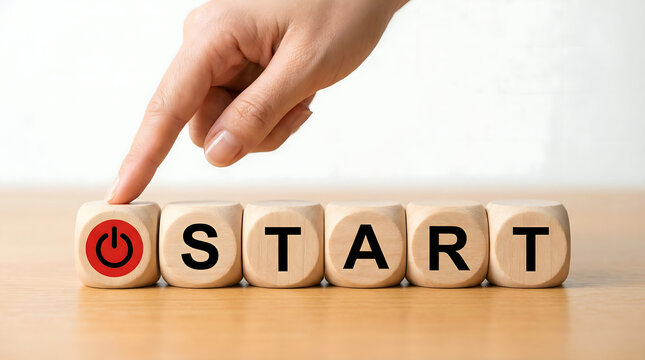 Hand presses 'Start' button on wooden cubes, symbolizing new beginnings and motivation