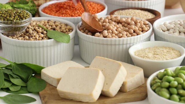 Woman with vegan products rich in protein at white table, closeup