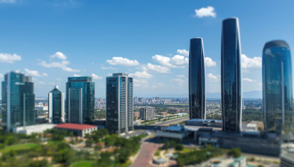 Naklejka premium Modern city skyline with glass skyscraper towers and blue sky reflecting sunlight, vibrant