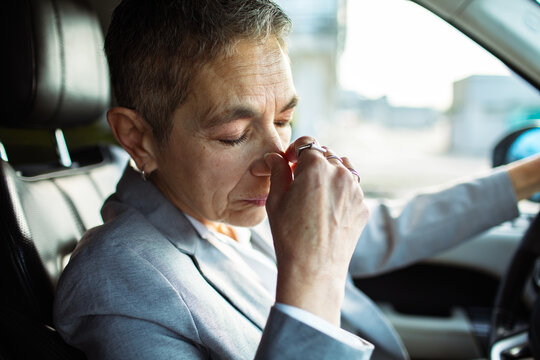 Stressed businessperson pinching nose bridge in car