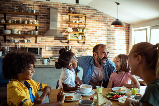 Happy family laughing together at breakfast in home kitchen