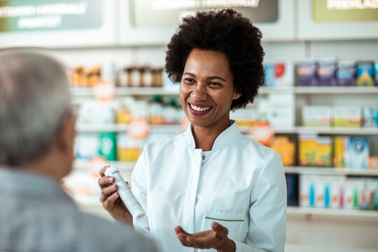 Smiling pharmacist advising senior customer in pharmacy