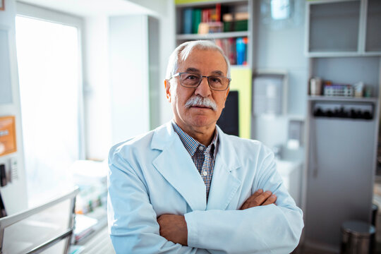 Senior male doctor with arms crossed in medical office