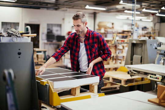 Male print worker checking sheets in factory