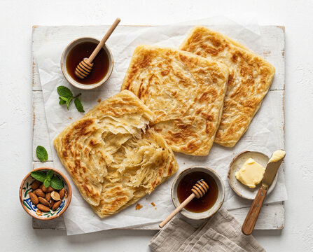Moroccan Msemen Layered Flatbread Pancakes with Flaky Interior Argan Honey and Butter on White Parchment White Background