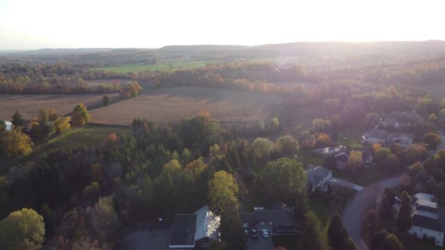 Aerial view of the Cheltenham area, a rural community within the town of Caledon, Ontario, Canada. Farming land on an autumn afternoon, flying west into the sun with sun flare and turning left.