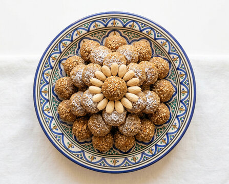 Moroccan Sellou Sfouf Roasted Flour Almond Energy Balls with Sesame Honey Anise Powdered Sugar on Traditional Ceramic Plate White Background